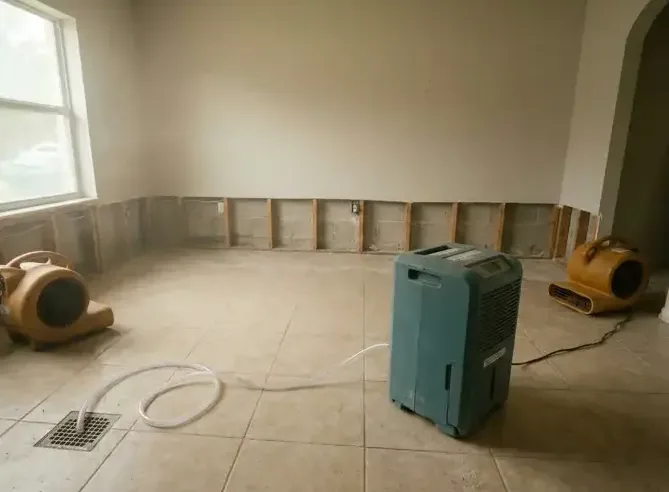Dehumidifier and air movers drying a room with the baseboards pulled off