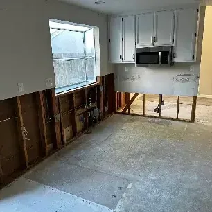 Hallway with the walls flood cut and the subfloor bare while drying equipment runs