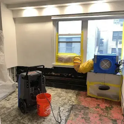 Dehumidifier and air mover running in a room after the floor covering was taken up