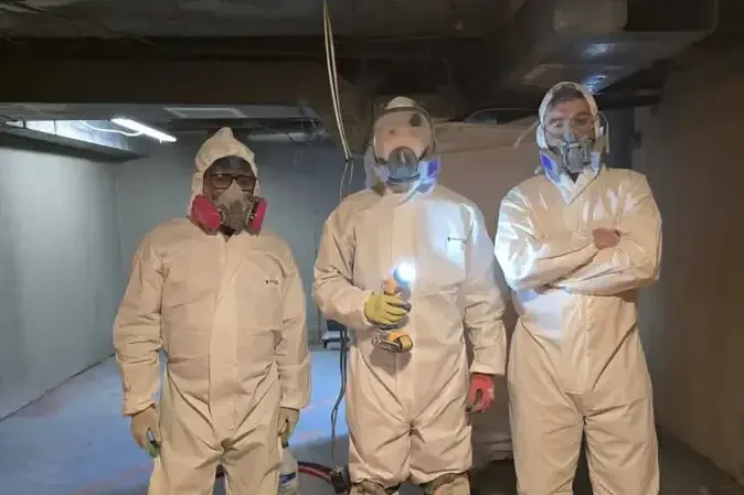 Crew in full protective suits working a lower level after a sewer backup